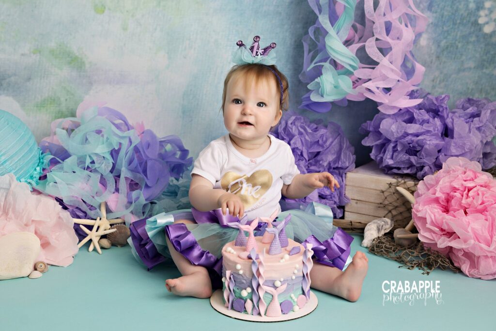 Smiling one year old during pastel mermaid cake smash setup
