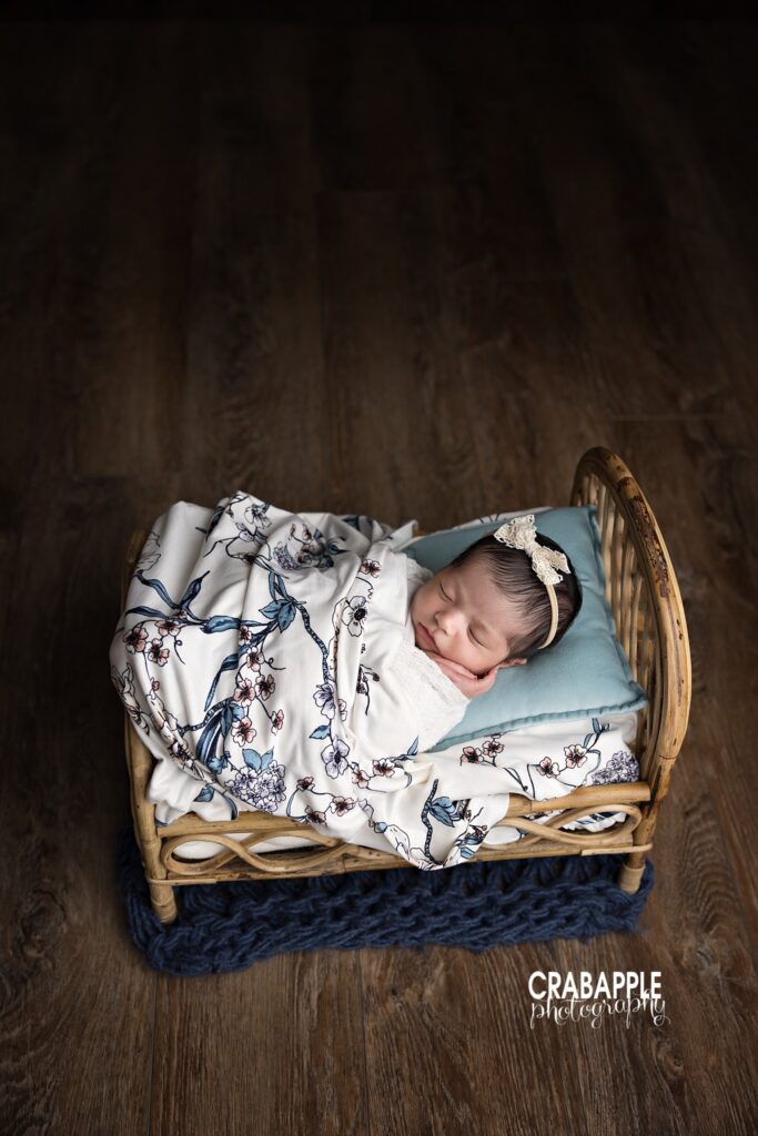 Floral Bed Portrait Newborn baby girl posed on rattan bed with floral wrap