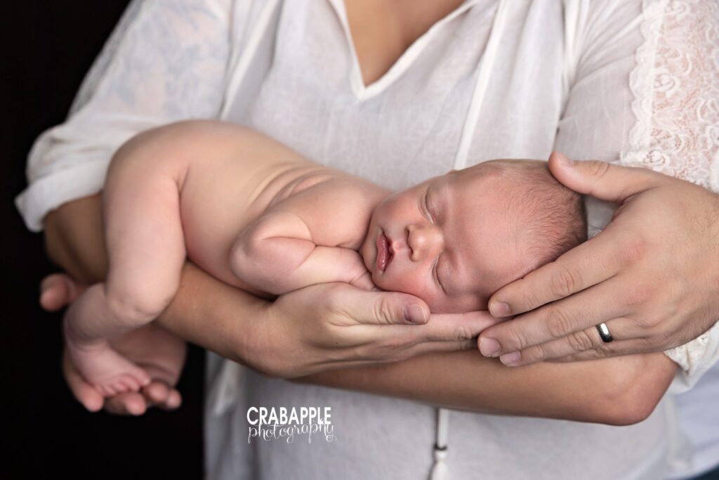 newborn baby boy cradled in parents arms during studio session
