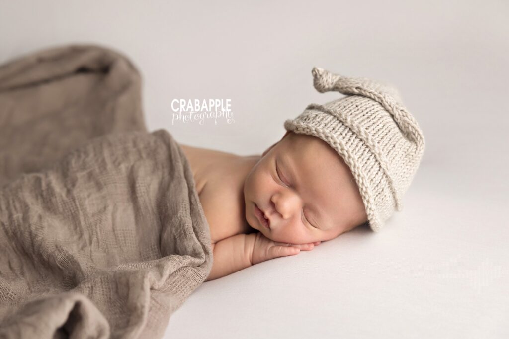 newborn baby boy wearing neutral knit hat while sleeping
