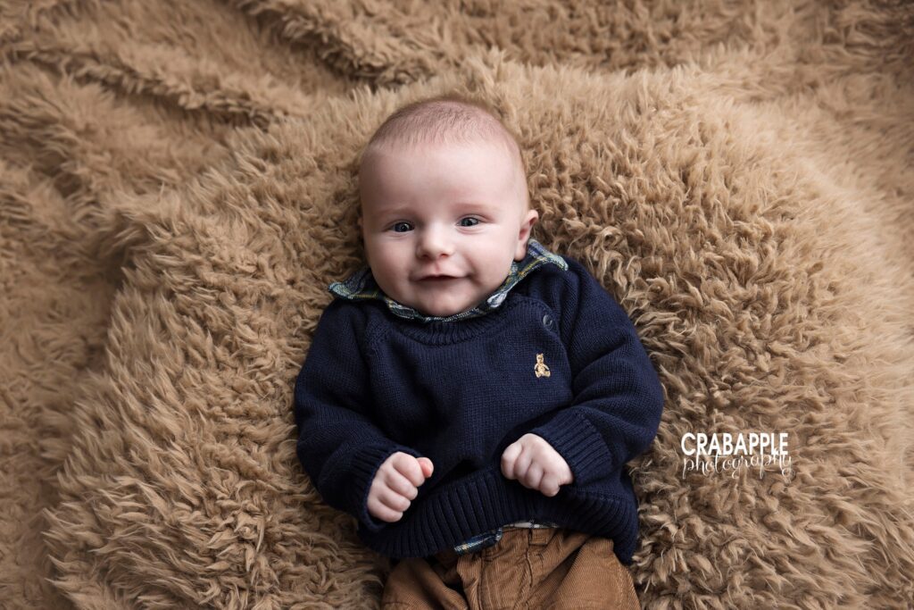 Baby boy wearing classic navy sweater and plaid shirt during milestone photos
