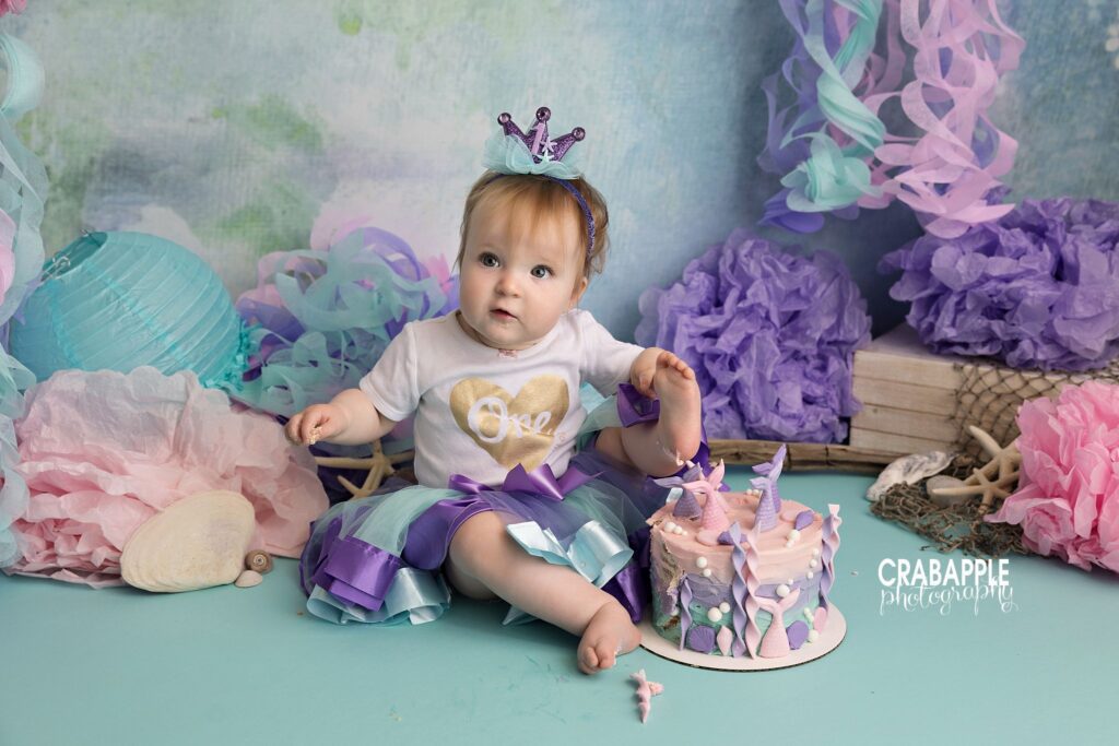 Mermaid themed cake smash with pastel ocean colors and floral decor
