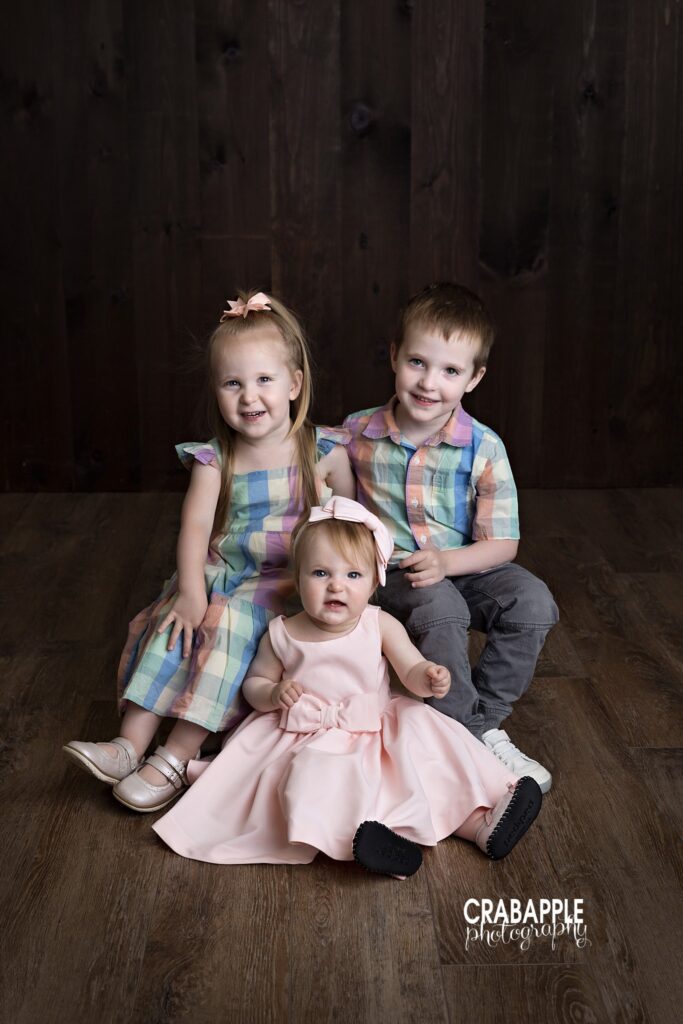 Brother and sisters smiling together in studio portrait session
