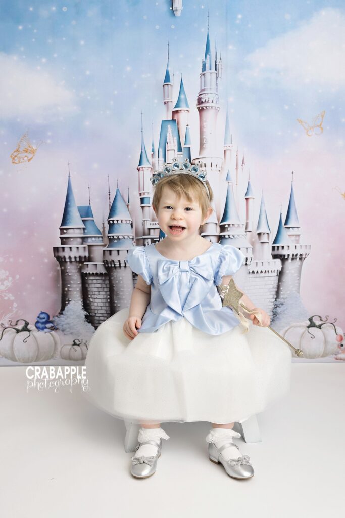 Whimsical toddler portrait with Cinderella castle backdrop and blue dress
