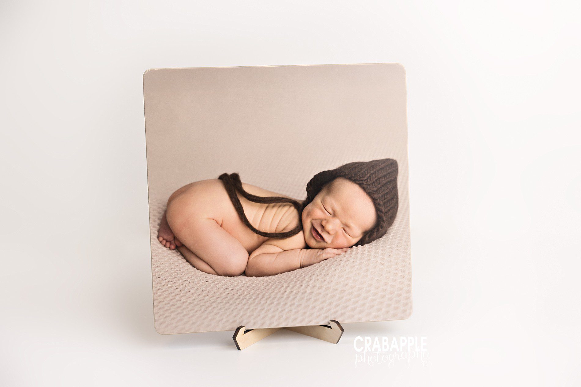 14x14 wood mounted newborn portrait displayed upright with matte finish and wooden stand
