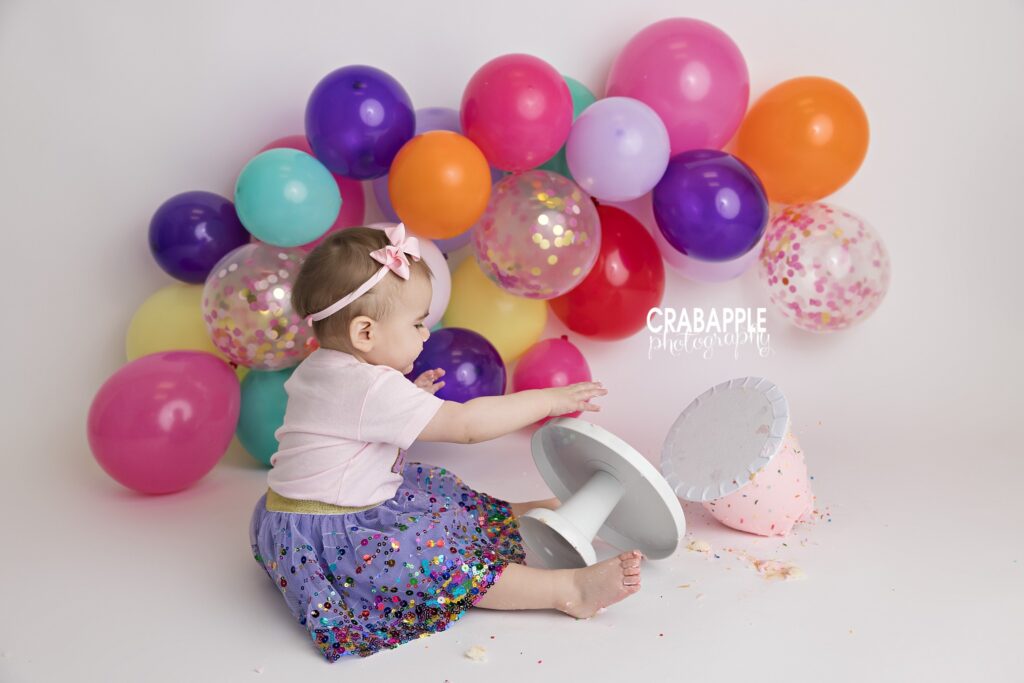 Cake Tumble One year old knocking birthday cake over during cake smash session