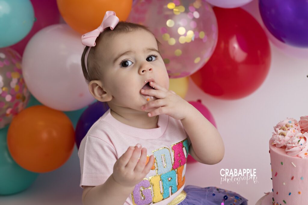 Sweet Birthday Moment One year old enjoying frosting-covered cake smash portrait