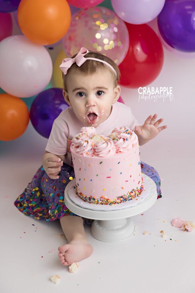 Cake Smash Fun Baby girl making funny expression while eating birthday cake