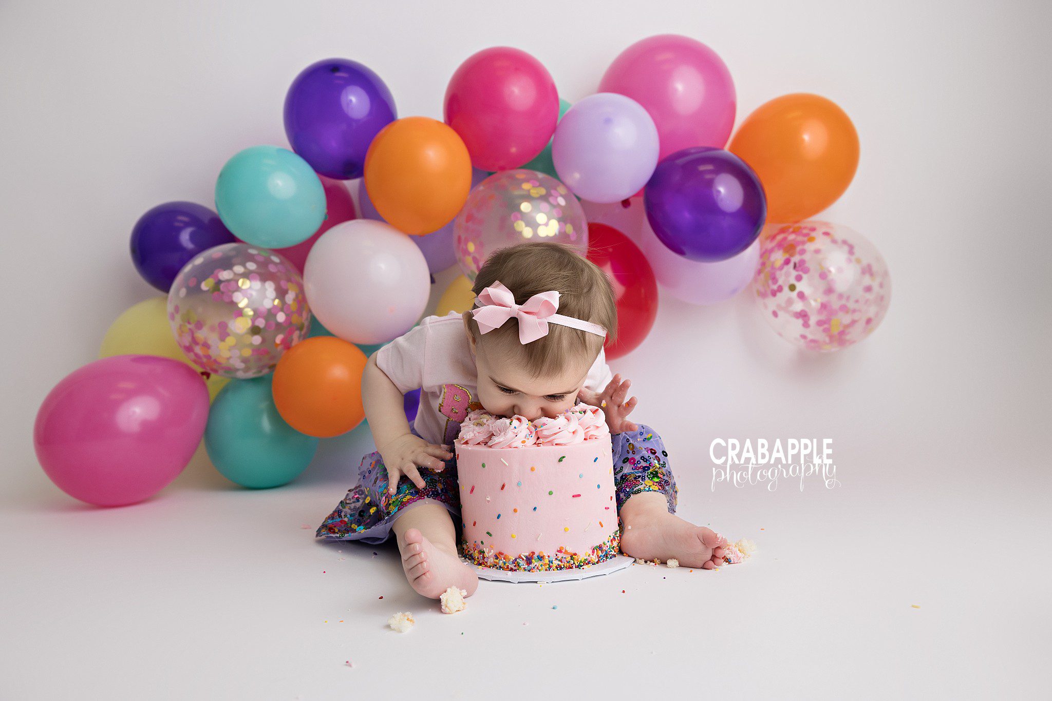 Birthday Celebration One year old girl happily eating birthday cake surrounded by balloons