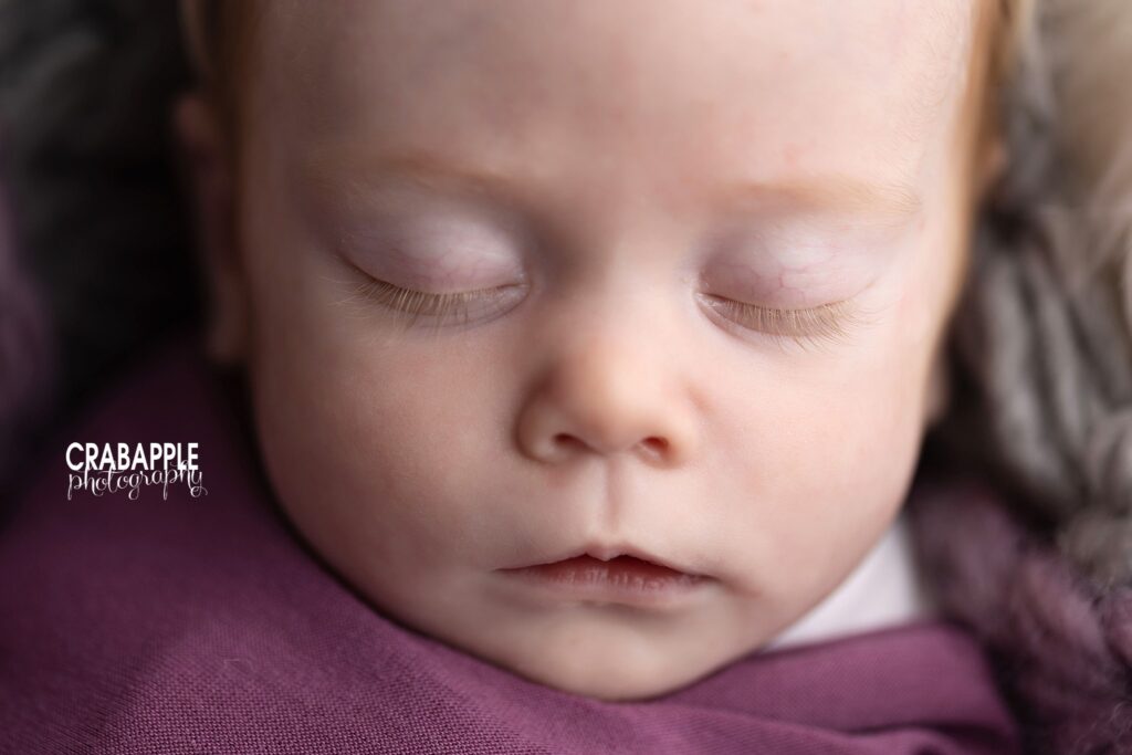 Detailed close-up of sleeping baby girl in purple swaddle

