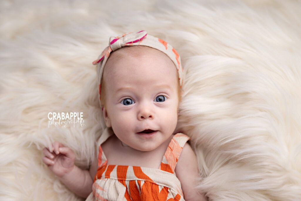 Three month old baby girl smiling in floral outfit during studio session

