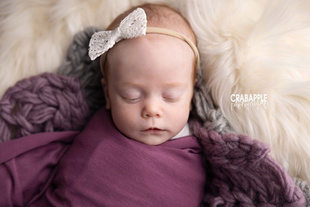 Close-up portrait of swaddled baby girl wrapped in purple

