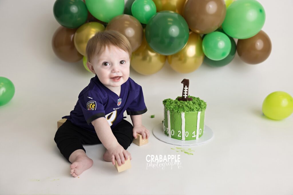 One year old milestone photography featuring football inspired birthday theme and sports themed cake smash