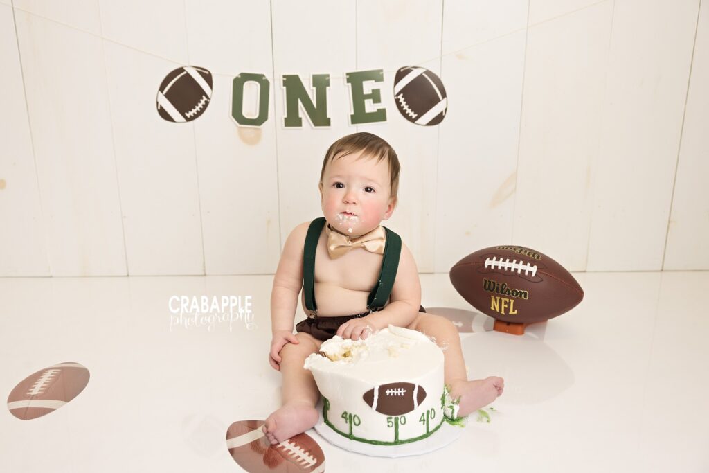 Football inspired first birthday cake smash photography session with sporty custom birthday setup