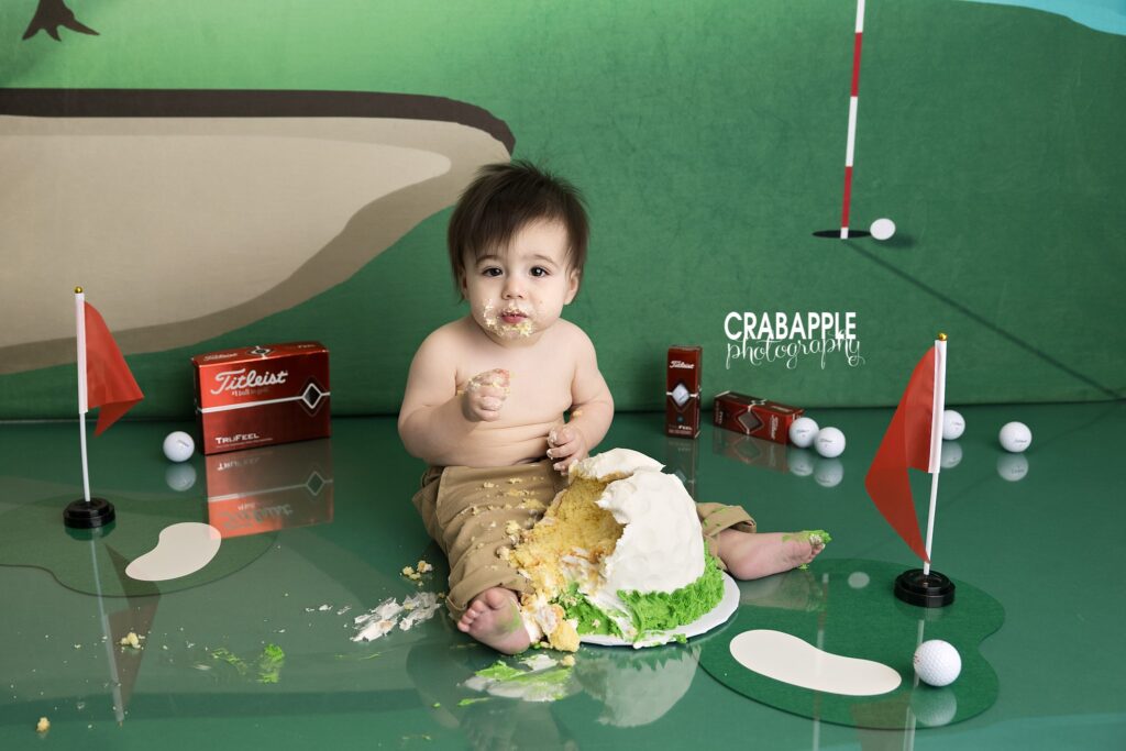 First birthday cake smash photography featuring golf themed decorations and playful sports inspired styling