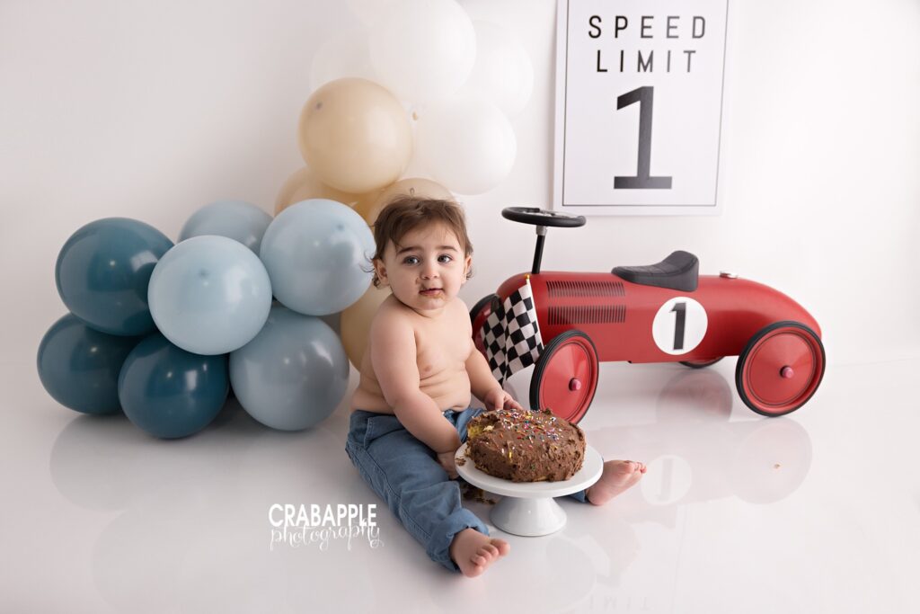 First birthday photos featuring race car cake smash theme and custom racing inspired decorations