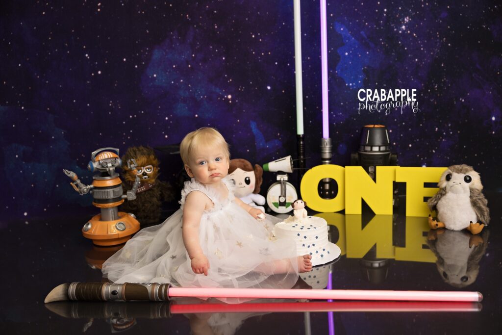 Baby girl with Star Wars props including Ewoks and lightsabers
