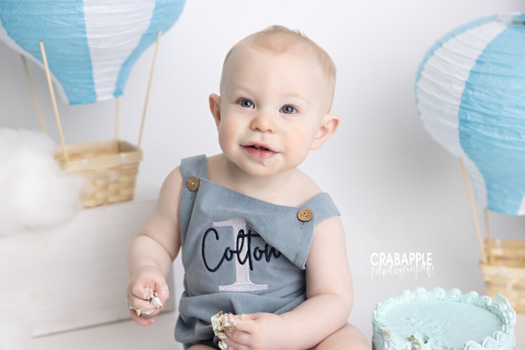 Hot Air Balloon First Birthday Little boy laughing during hot air balloon themed cake smash