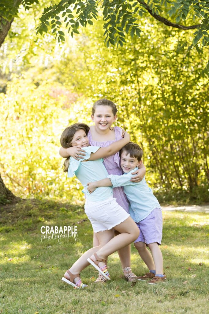 Three siblings sharing a candid hug at the Acton Arboretum

