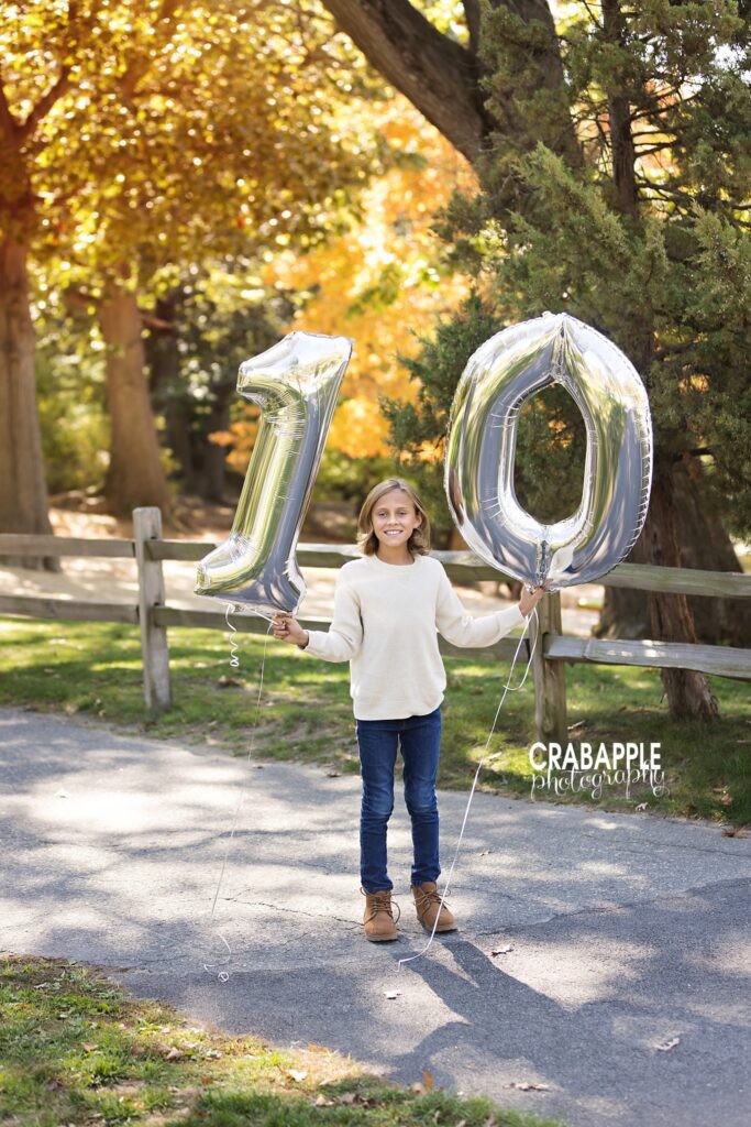 Fall birthday portrait with age balloon Child holding a balloon showing their age during fall family photos in Medford MA