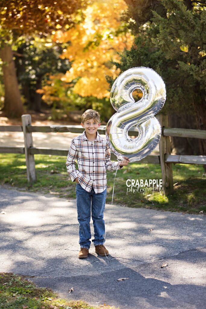 Child fall portrait with age balloon Child holding an age balloon during a fall portrait session in Medford MA