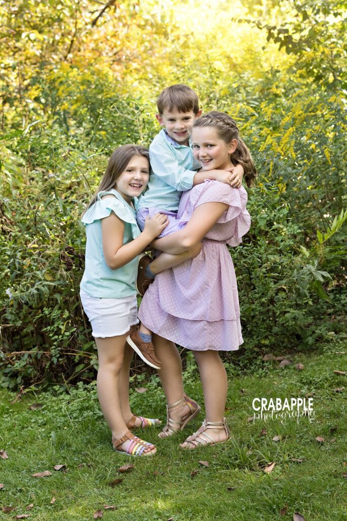 Three siblings smiling together during an outdoor family session in Acton MA
