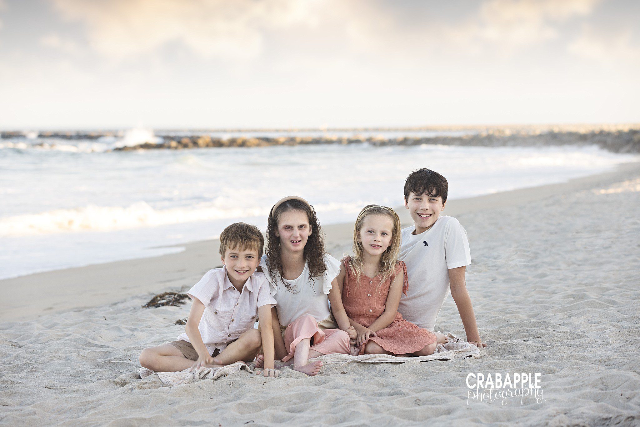 Four siblings sitting together on a blanket at Salisbury Beach Reservation
