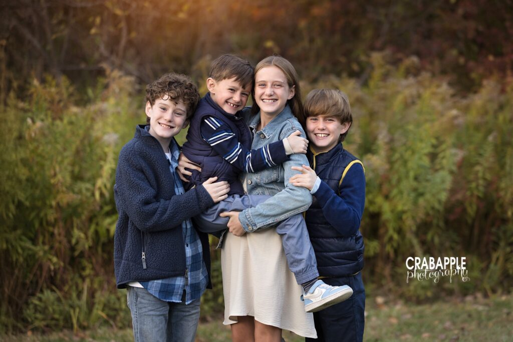 Four siblings smiling together during an outdoor fall family session at Ipswich River Park
