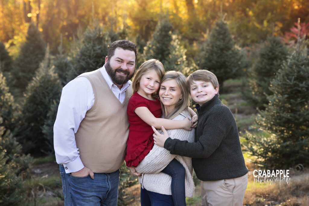 Family cuddle Family of four sharing a cuddle among the evergreen trees at the tree farm