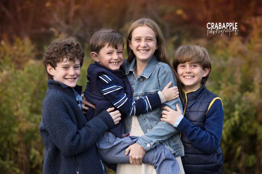 Four siblings gathered together for playful fall portraits in North Reading Massachusetts

