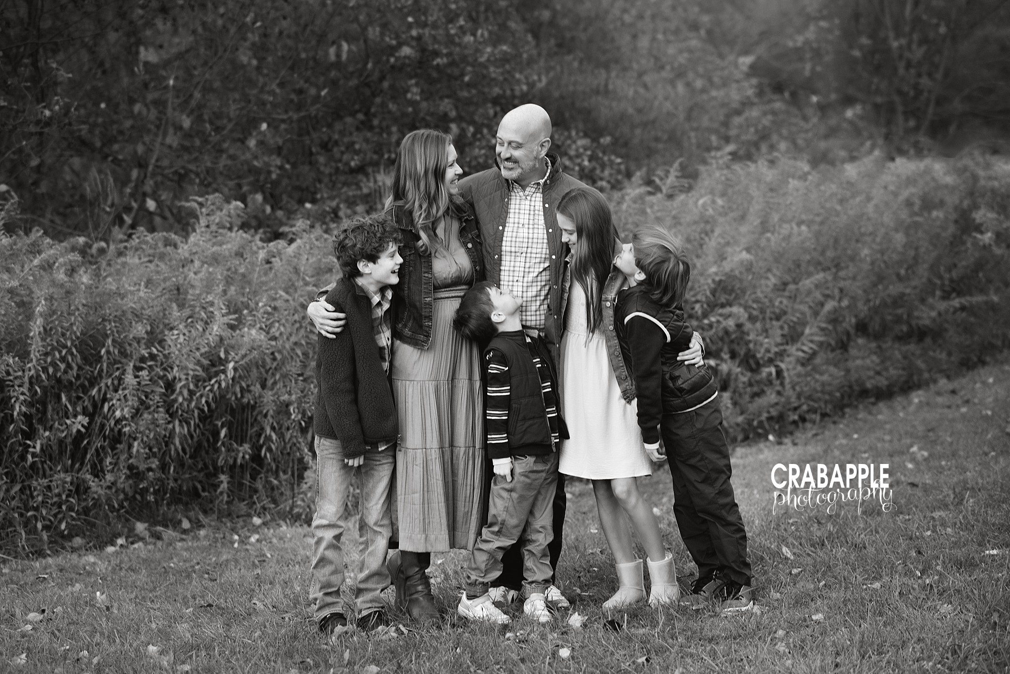 Black and white portrait of an Andover family of six looking at each other during fall photos
