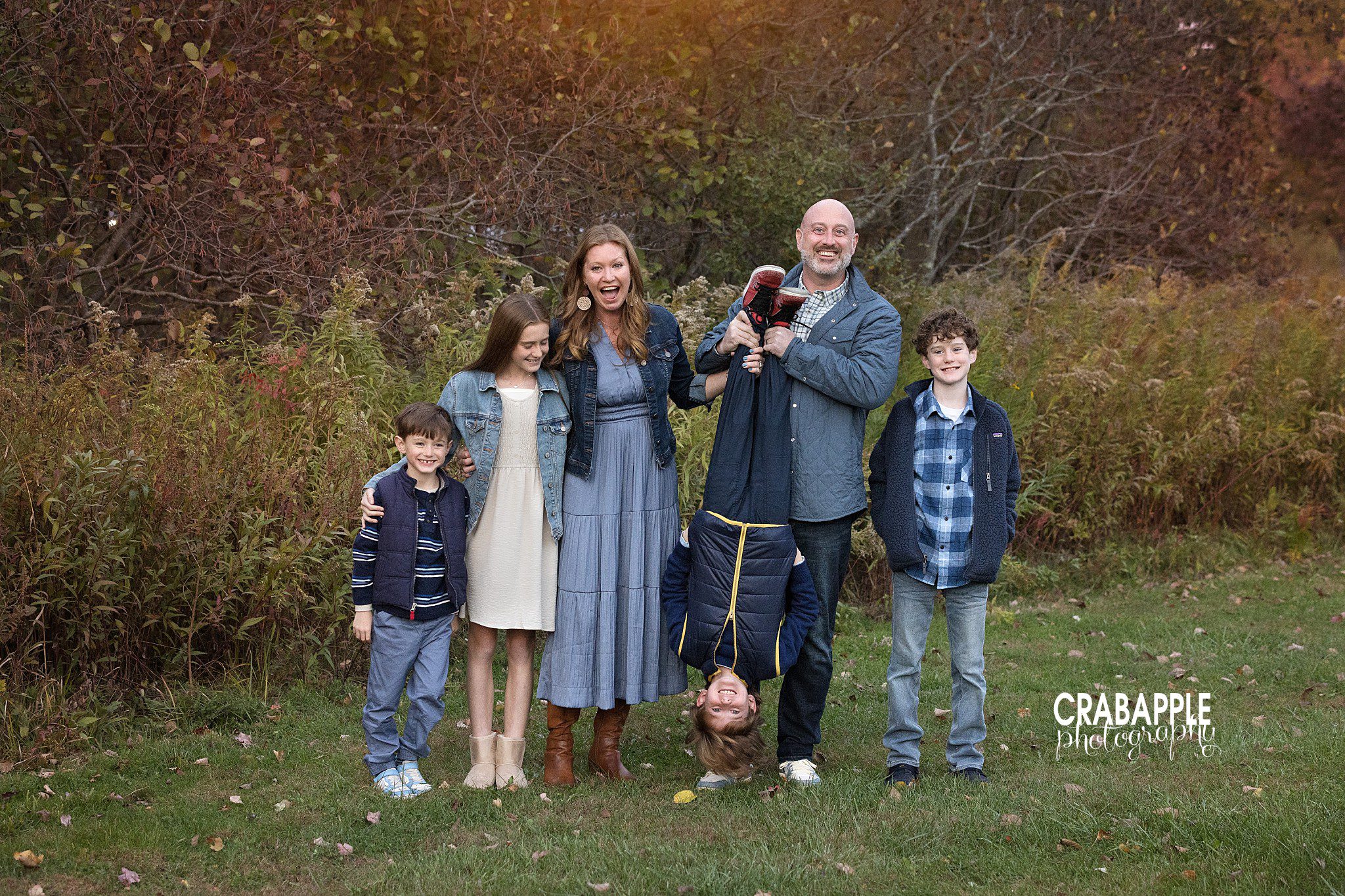Dad playfully holding his young son upside down during outdoor family photos in North Reading MA
