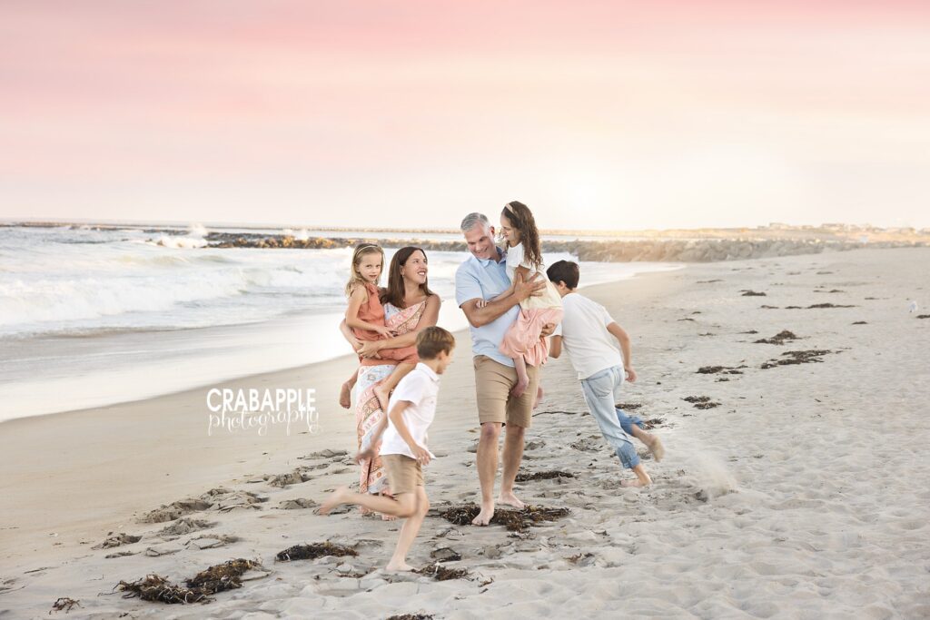 Parents carrying daughters while two sons run beside them on Salisbury Beach
