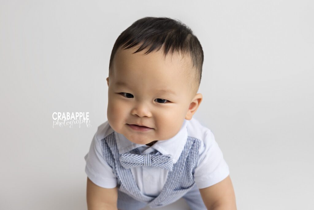 Close up portrait of 10 month old boy in front of a white backdrop during milestone baby session