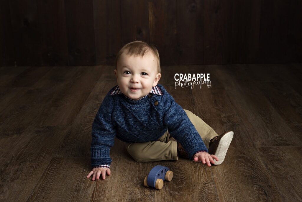 Baby boy playing with a toy car during his 1-year portraits Baby boy in a navy sweater playing with a toy car during his 1-year session