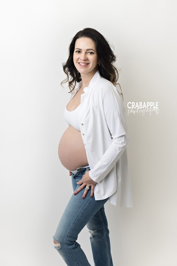 Casual jeans and white shirt maternity look Expecting mother wearing jeans and an unbuttoned white shirt during her studio maternity session