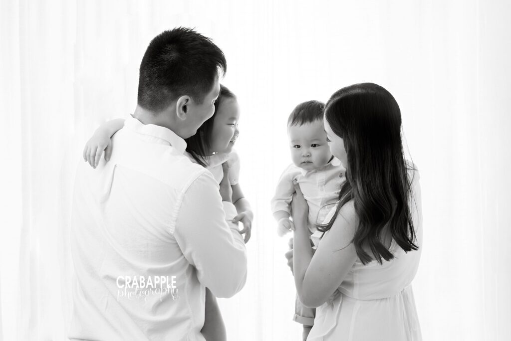 Black and white family portrait of a candid moment during a family and baby milestone session