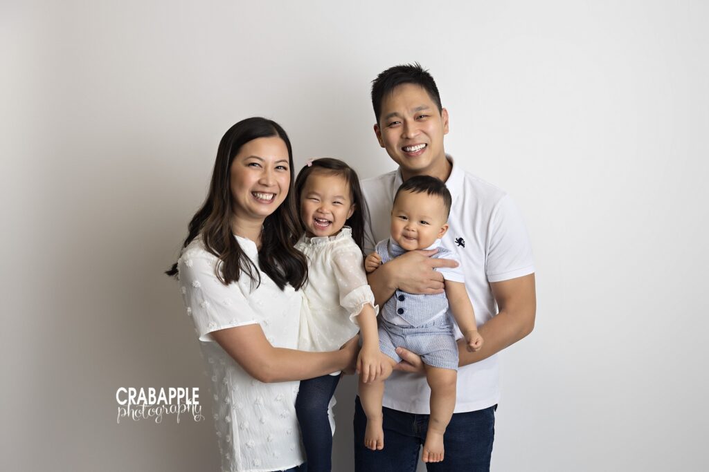 Family of four photographed together in a light and airy studio setting