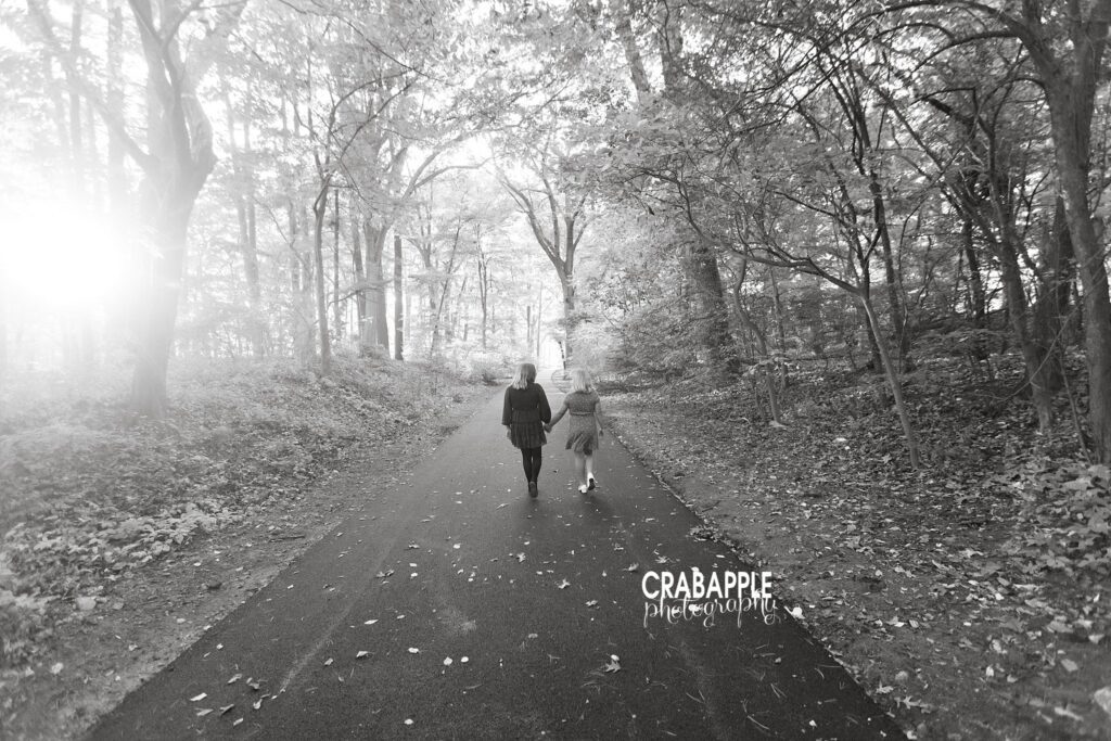 Black and white tree lined path sisters Black and white photo of two sisters walking along a tree lined path during Medford MA family photos in fall