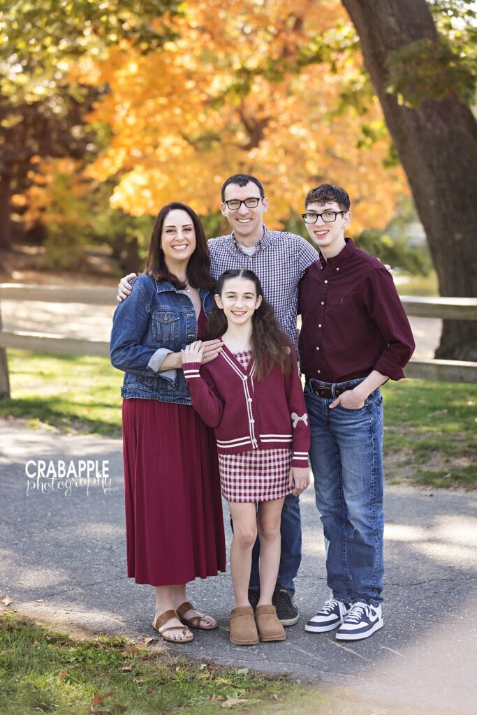 Family standing together beneath colorful autumn trees in Medford Massachusetts