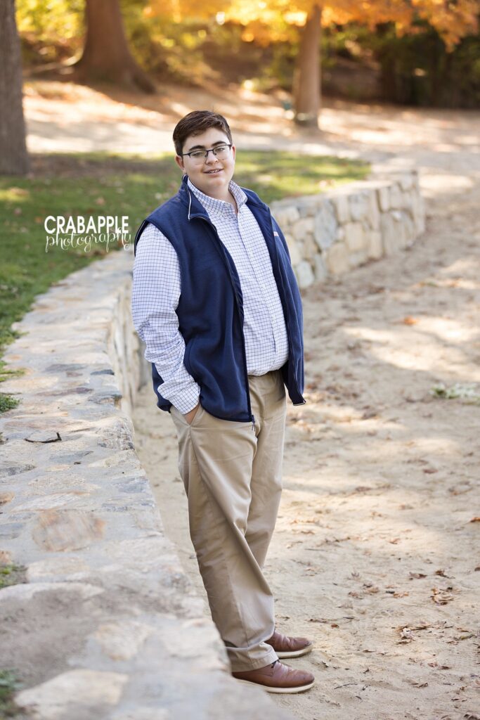 young man in khakis, a button down and a vest poses for fall family photos