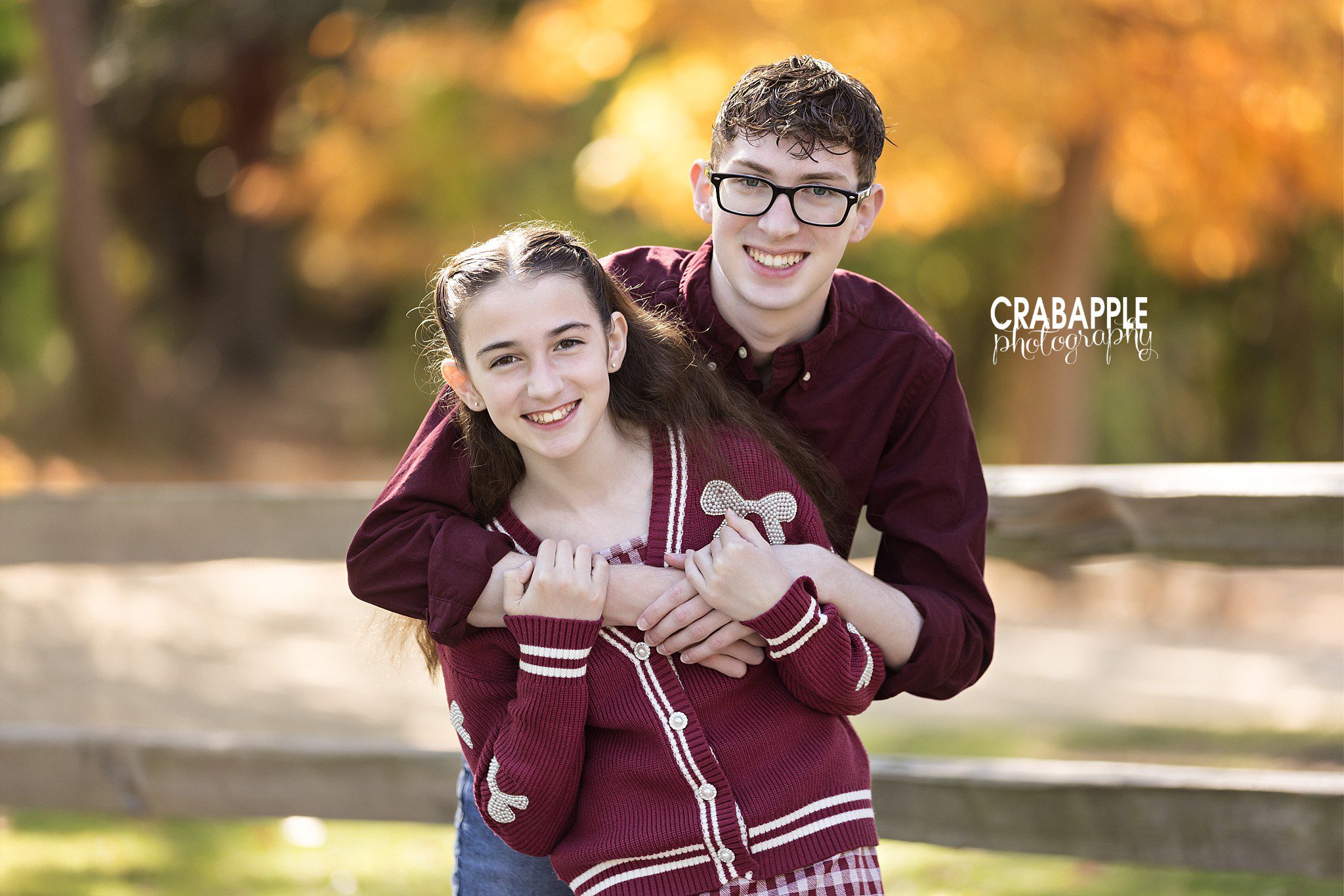 Two siblings wear coordinating button down and cardigan outfits for fall outdoor family photos