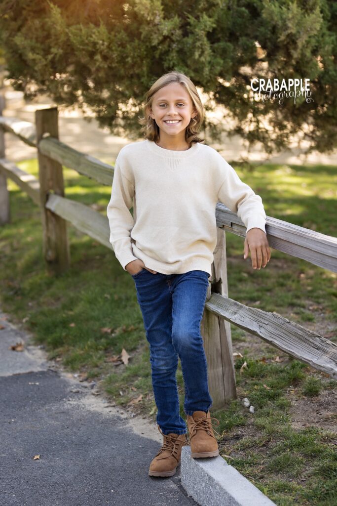 Young boy standing on a park path surrounded by autumn foliage in Medford