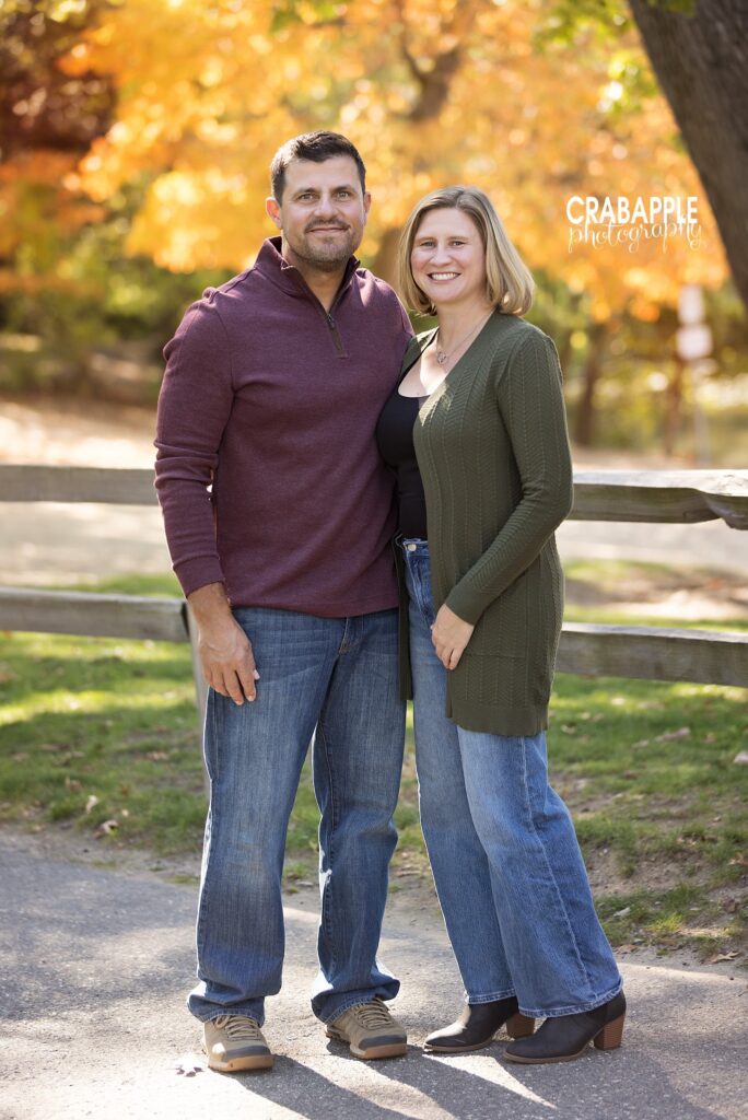 Couple standing together on a tree-lined path during a fall portrait session in Medford