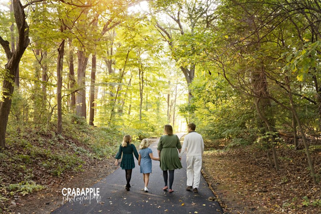 Family walking together along a tree-lined path during a fall photo session in Medford