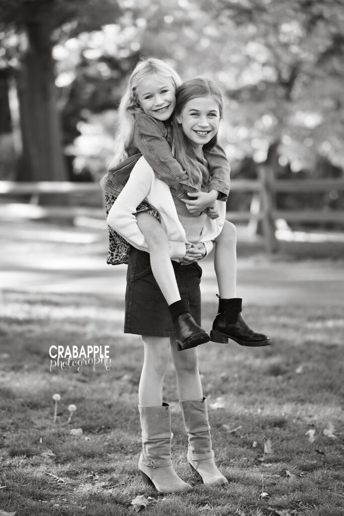 Playful black and white sibling portrait Two sisters playing together during a black and white fall portrait