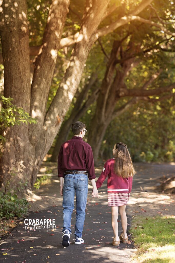 Siblings walking together Brother and sister walking together along a park path during fall photos in Medford
