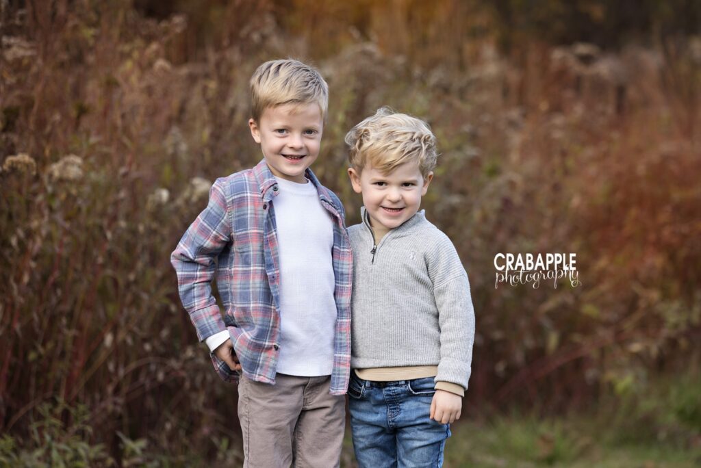 Two siblings standing together among autumn foliage at Ipswich River Park