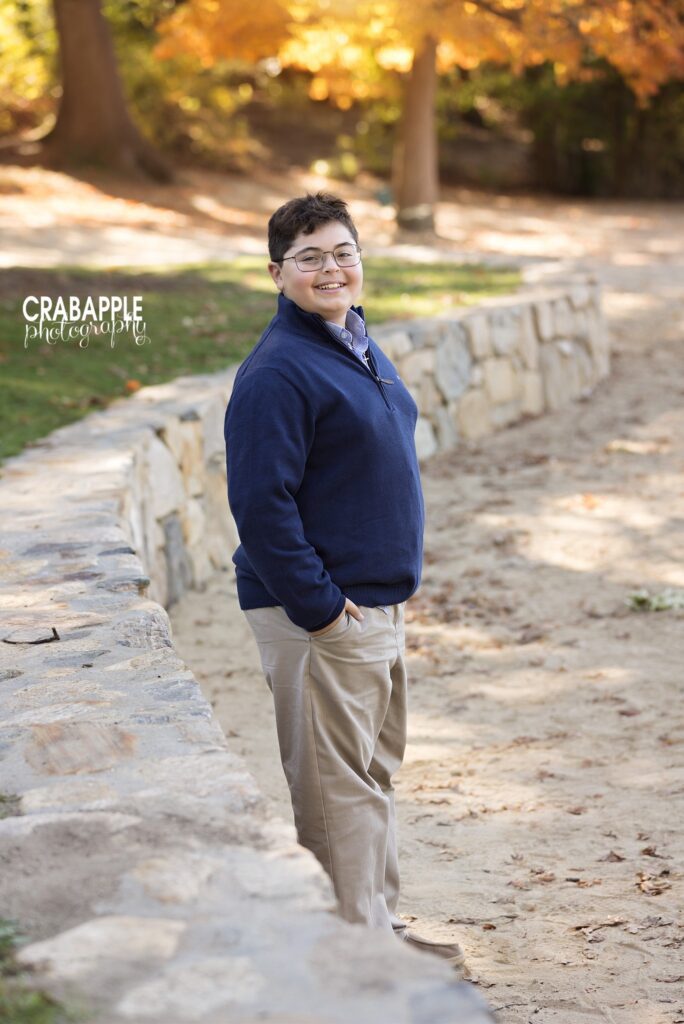 Young man in a pullover and khakis poses for photos in fall