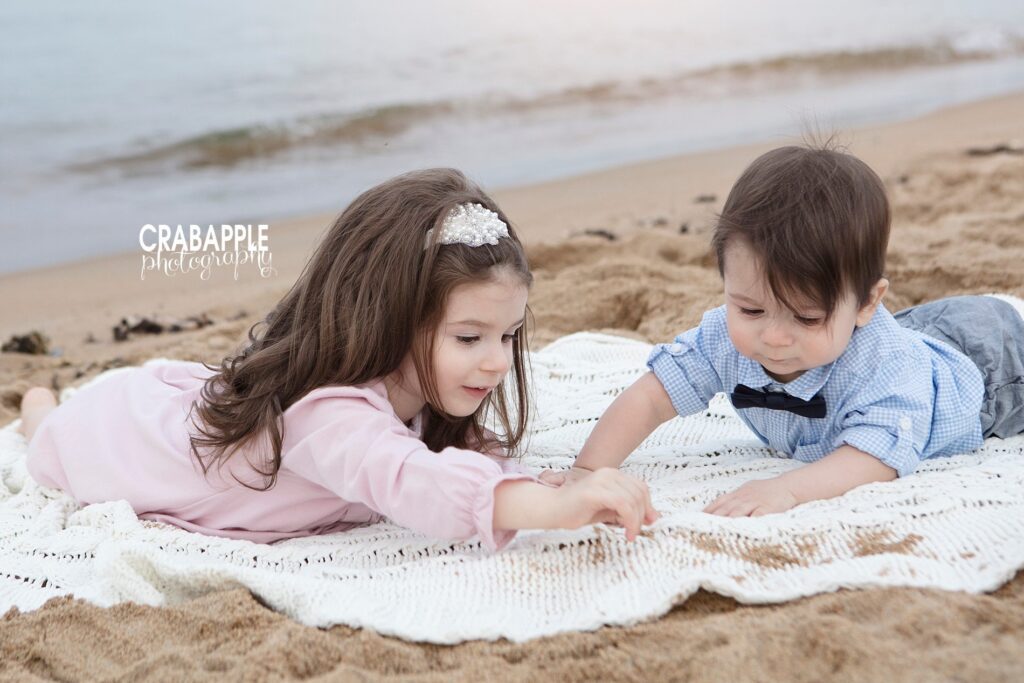 Two siblings play in the sand during beach photos